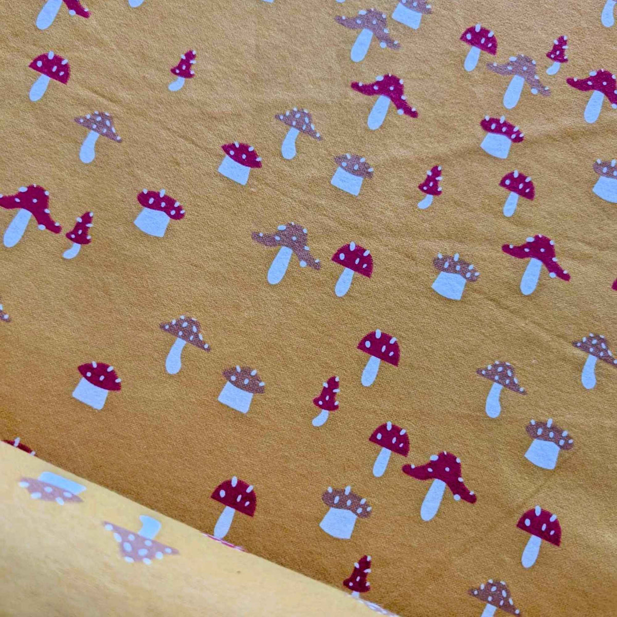 Red Mushroom Flannel on Tan 
background.
Golden yellow flannel fabric with whimsical red and tan mushroom print – 100% cotton, soft and cozy for quilting, pajamas, and crafts