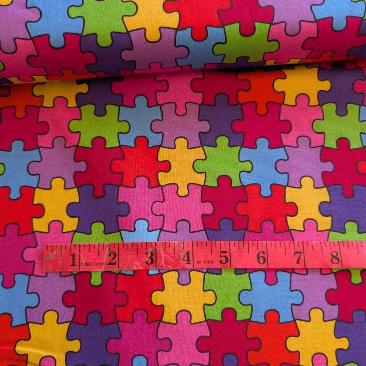 Multicolour Autism Awareness puzzle piece cotton fabric with red, blue, green, yellow, and purple jigsaw pattern
