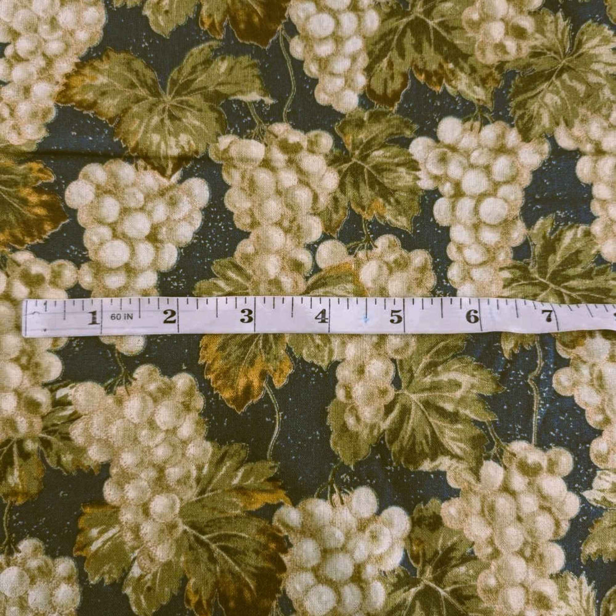Nature’s Harvest cotton fabric by Robert Kaufman featuring green grape clusters and vine leaves on green with gold accents