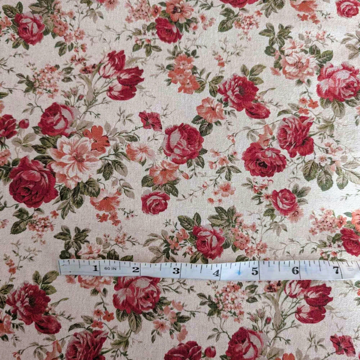 Vintage-inspired cotton flax fabric with red roses and green leaves on a natural beige background – ideal for home décor, quilting, and crafts