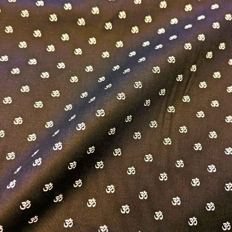 Black cotton fabric with small repeating white Om symbols, perfect for meditation and yoga-inspired projects.