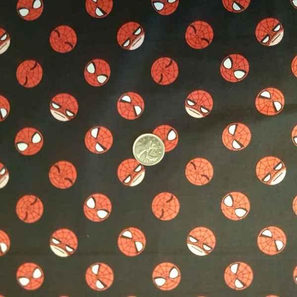 Camelot Fabrics Spiderman Emoji Faces fabric 13250102 with red cartoon Spiderman heads on black background with coin for scale.