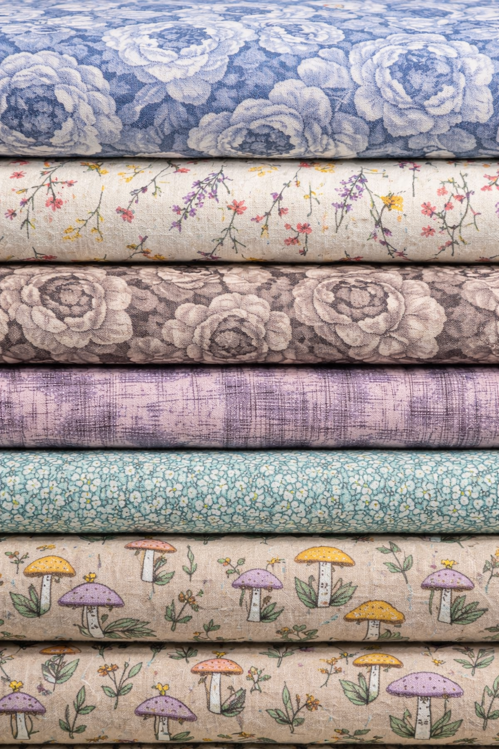 Stacked rolls of 108-inch wide brushed cotton flannel quilt backing fabrics featuring floral, textured, and mushroom prints in soft blue, cream, taupe, mauve, and aqua tones.