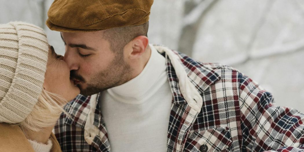 Man in plaid shirt kissing woman in winter