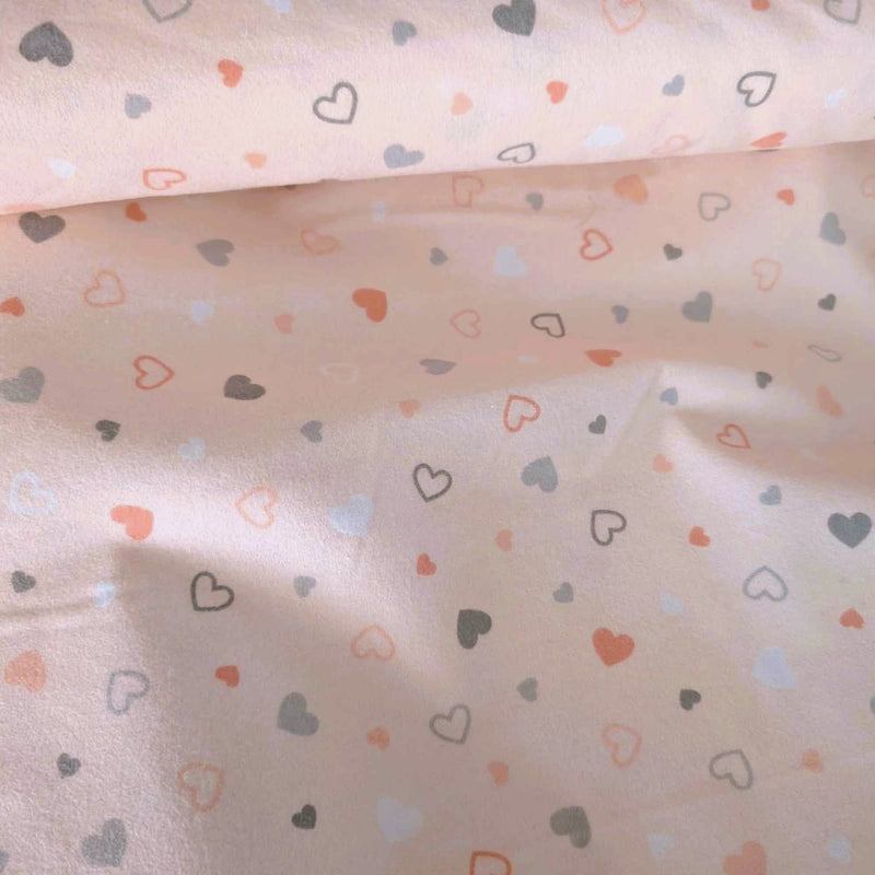 Pearl pink printed cotton flannel fabric with scattered pastel heart design by Robert Kaufman