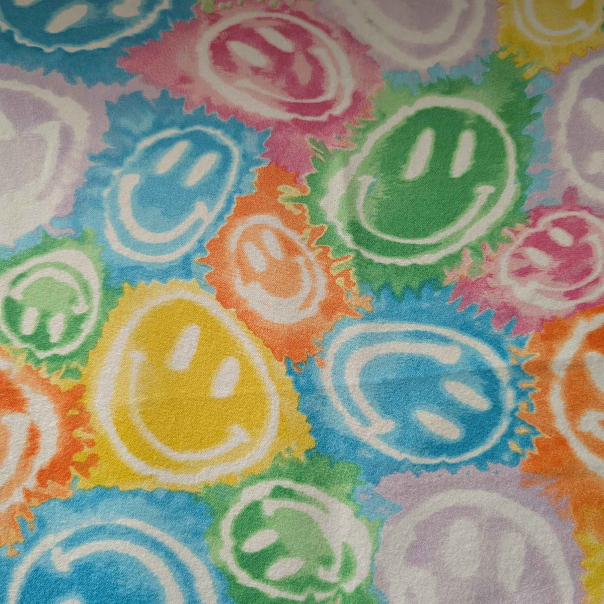 Rainbow smiley faces cotton flannel fabric with colorful tie-dye style print in green, yellow, pink, purple, orange, and blue. Brushed soft, OEKO-TEX certified, 44 inches wide.