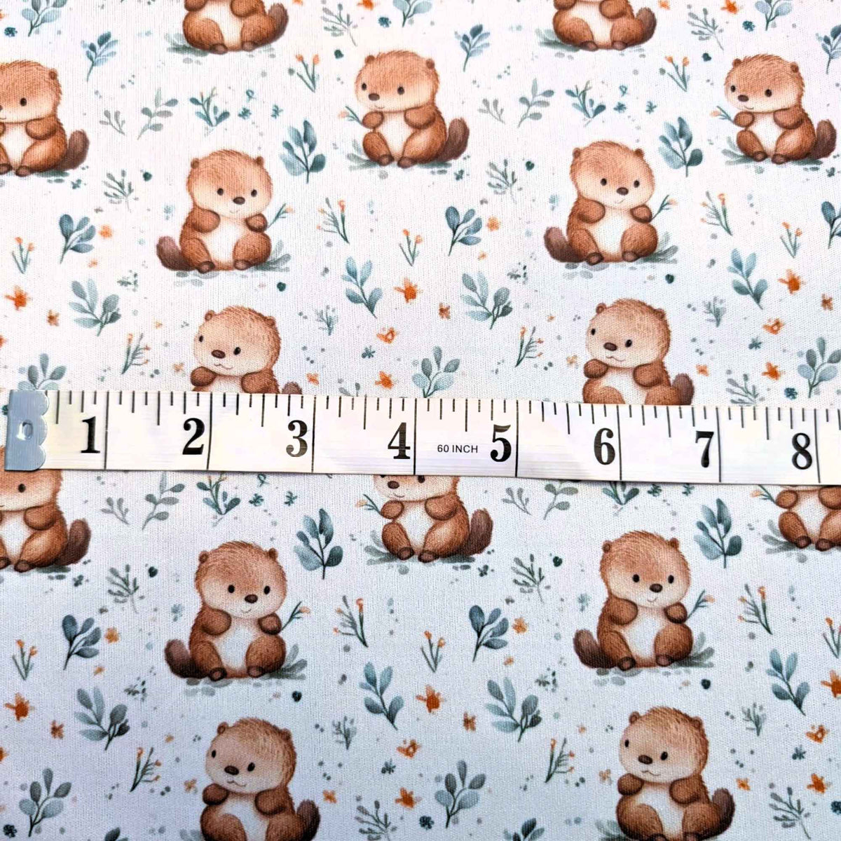 Woodland hedgehog waterproof PUL fabric with soft brown hedgehogs and green leaves on a neutral background