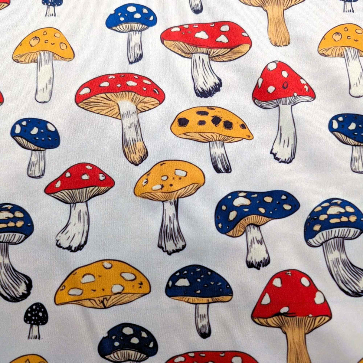 Red yellow and blue mushroom print food safe waterproof PUL fabric on neutral background, 60 inch wide polyester laminate.