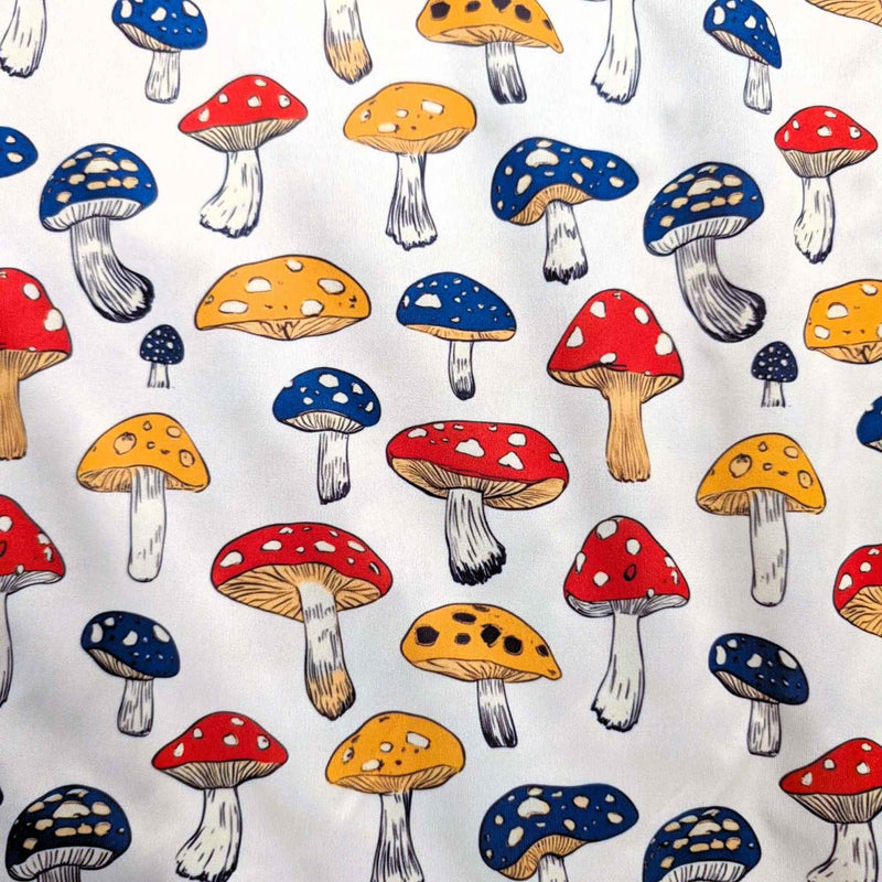 Red yellow and blue mushroom print food safe waterproof PUL fabric on neutral background, 60 inch wide polyester laminate.