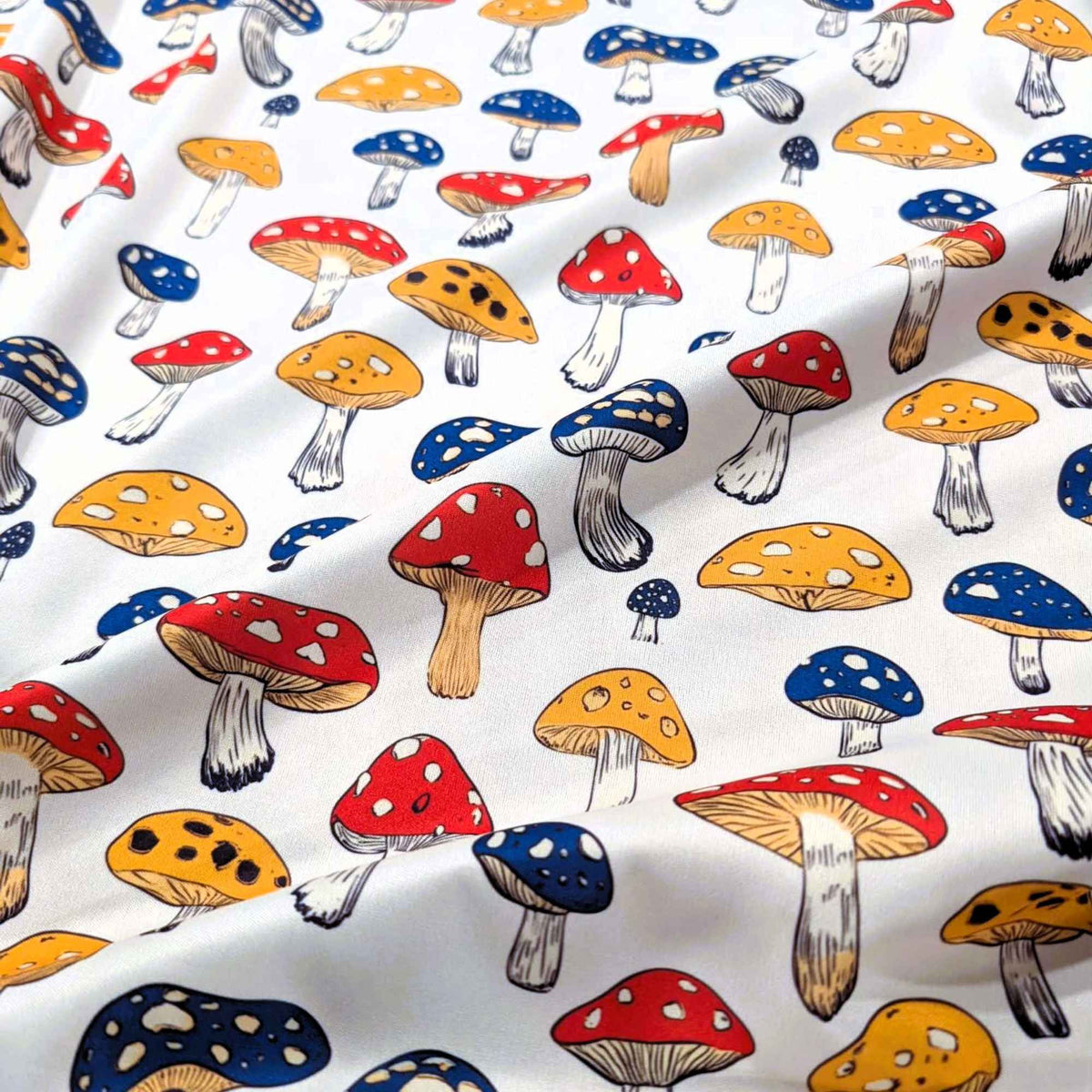 Red yellow and blue mushroom print food safe waterproof PUL fabric on neutral background, 60 inch wide polyester laminate.