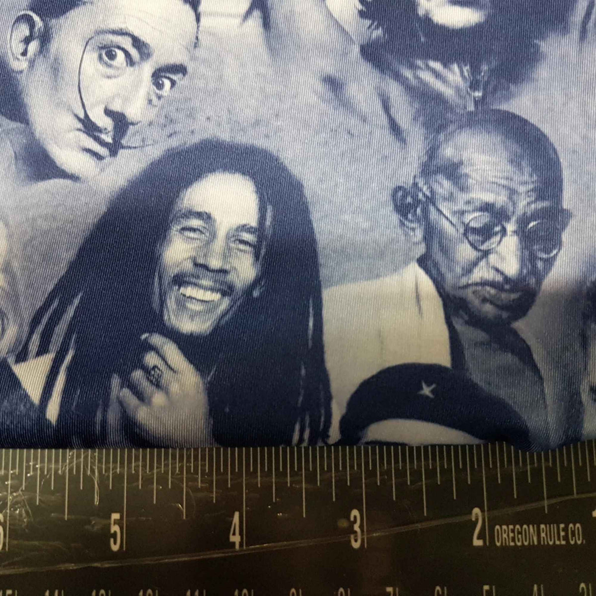 Blue grey polyester spandex fabric featuring portraits of Albert Einstein, Bob Marley, and other iconic figures in a repeating print