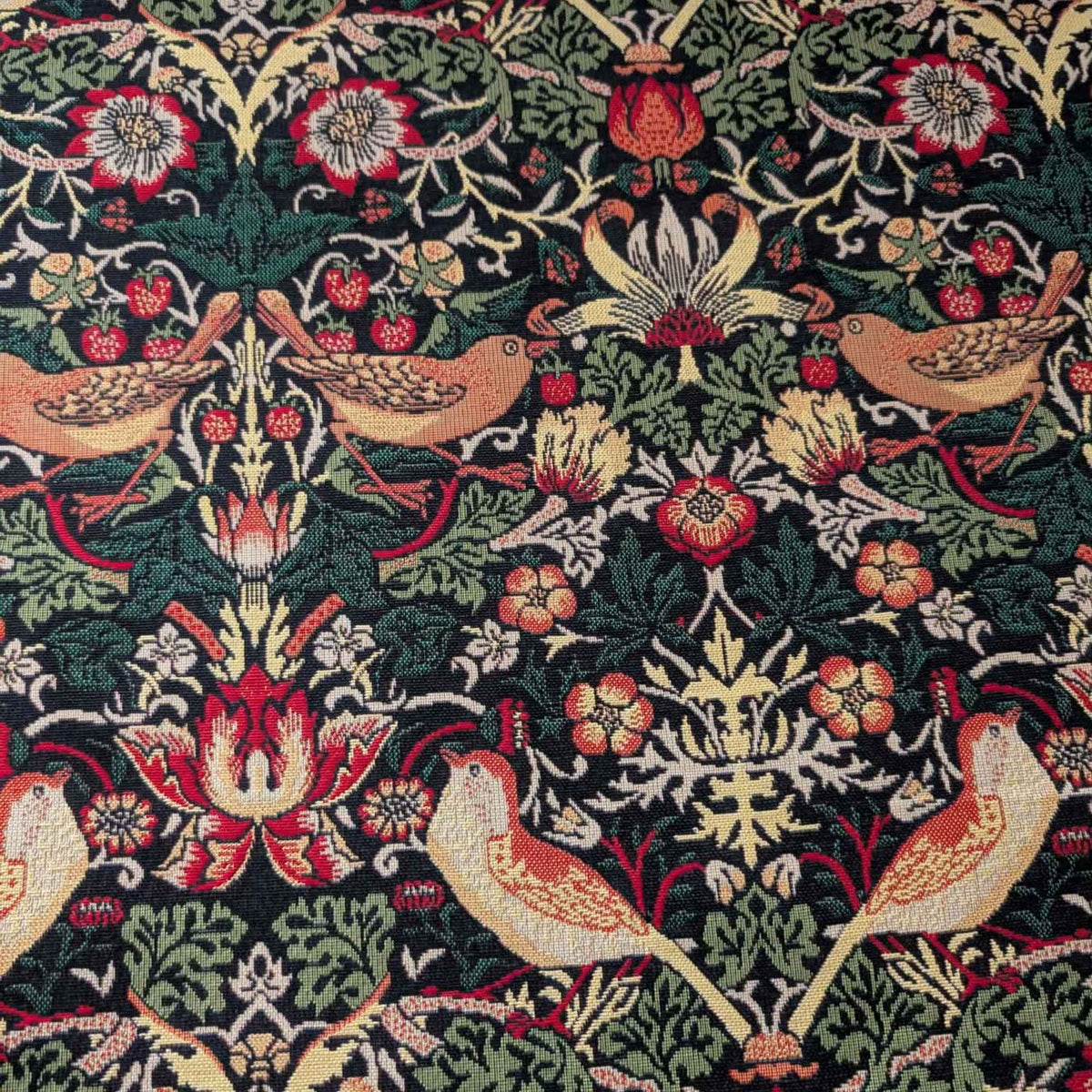 Black Gobelin tapestry fabric featuring golden birds, red strawberries, ornate flowers and scrolling green foliage.