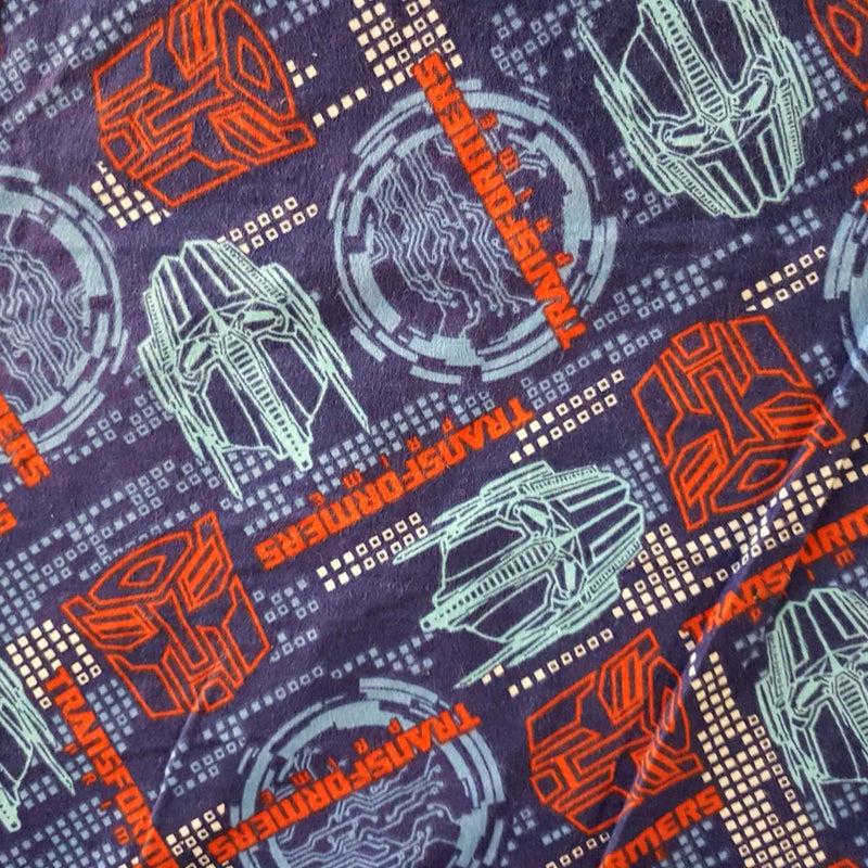 Transformers cotton flannel fabric with colorful robot designs and logos on a dark background, 44-inch wide kids character fabric