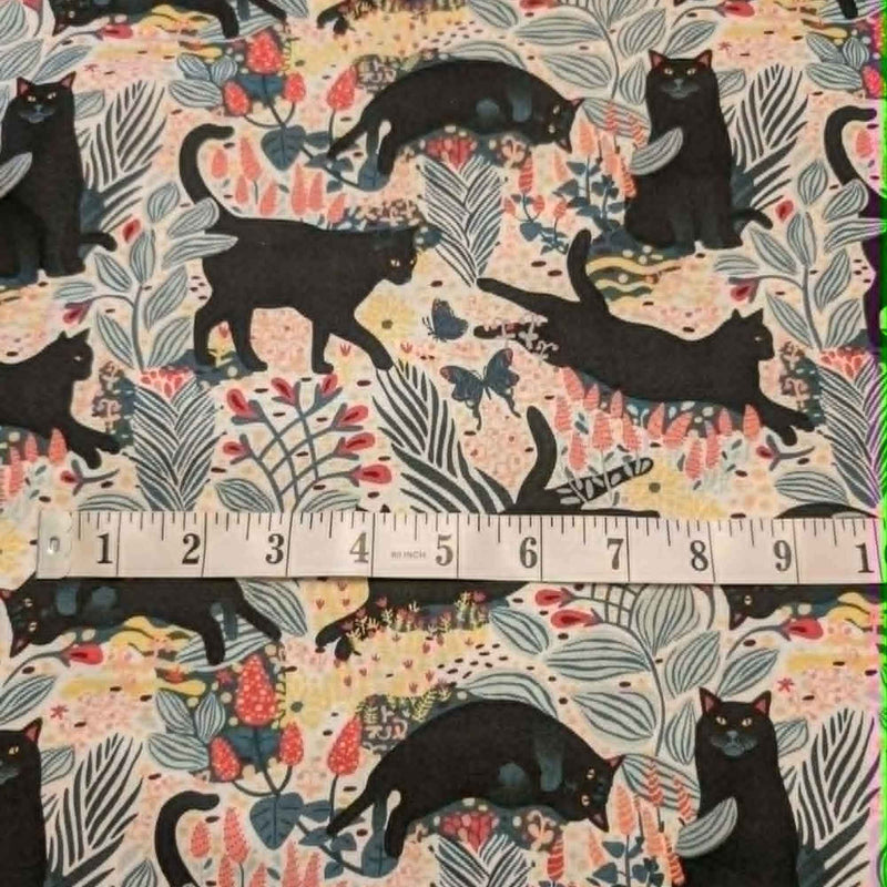 Black cat floral novelty quilting cotton fabric with leaves and butterflies on a light background