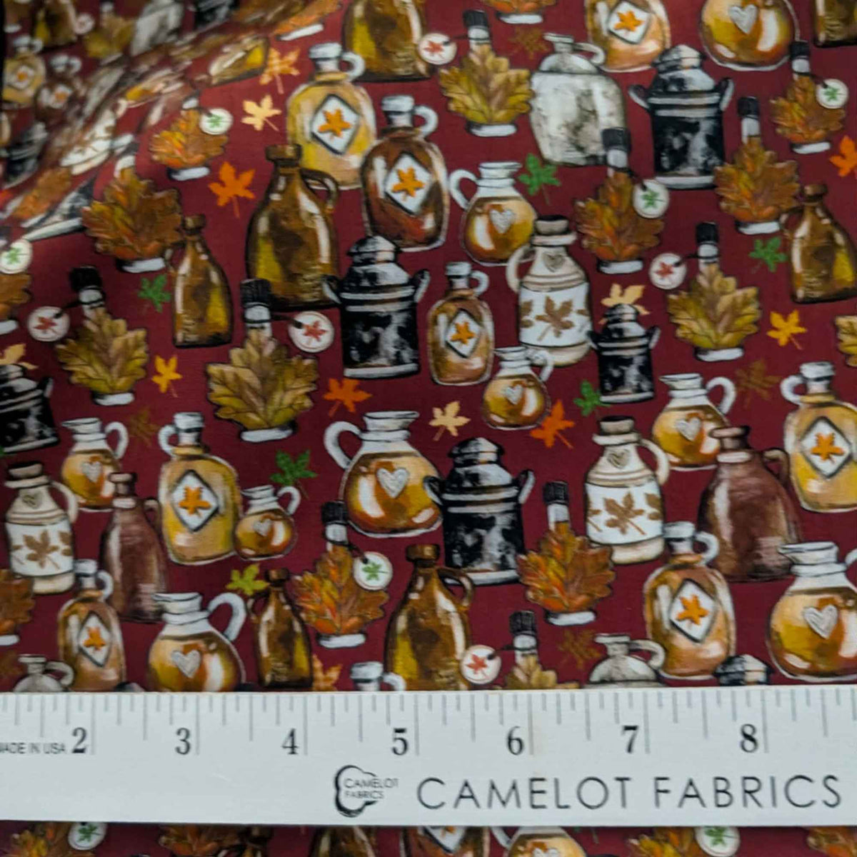 Autumn maple syrup jugs and fall leaves cotton fabric on red background with rustic harvest theme