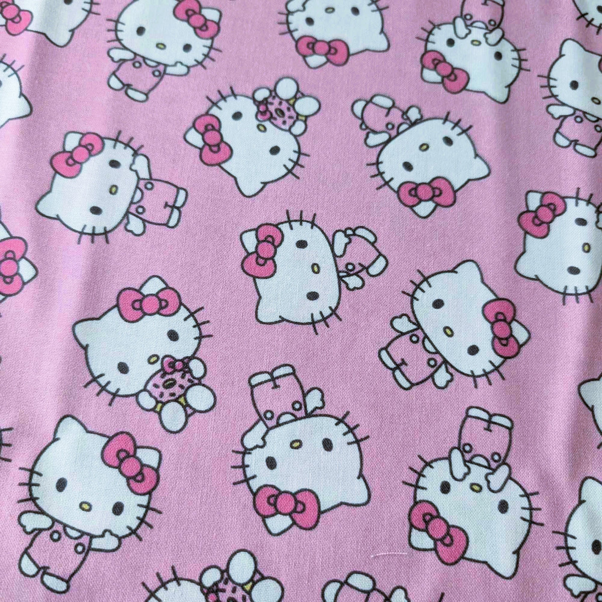 Officially licensed Hello Kitty cotton fabric by Springs Creative featuring an all-over toss of Hello Kitty holding a teddy bear on a pink background.