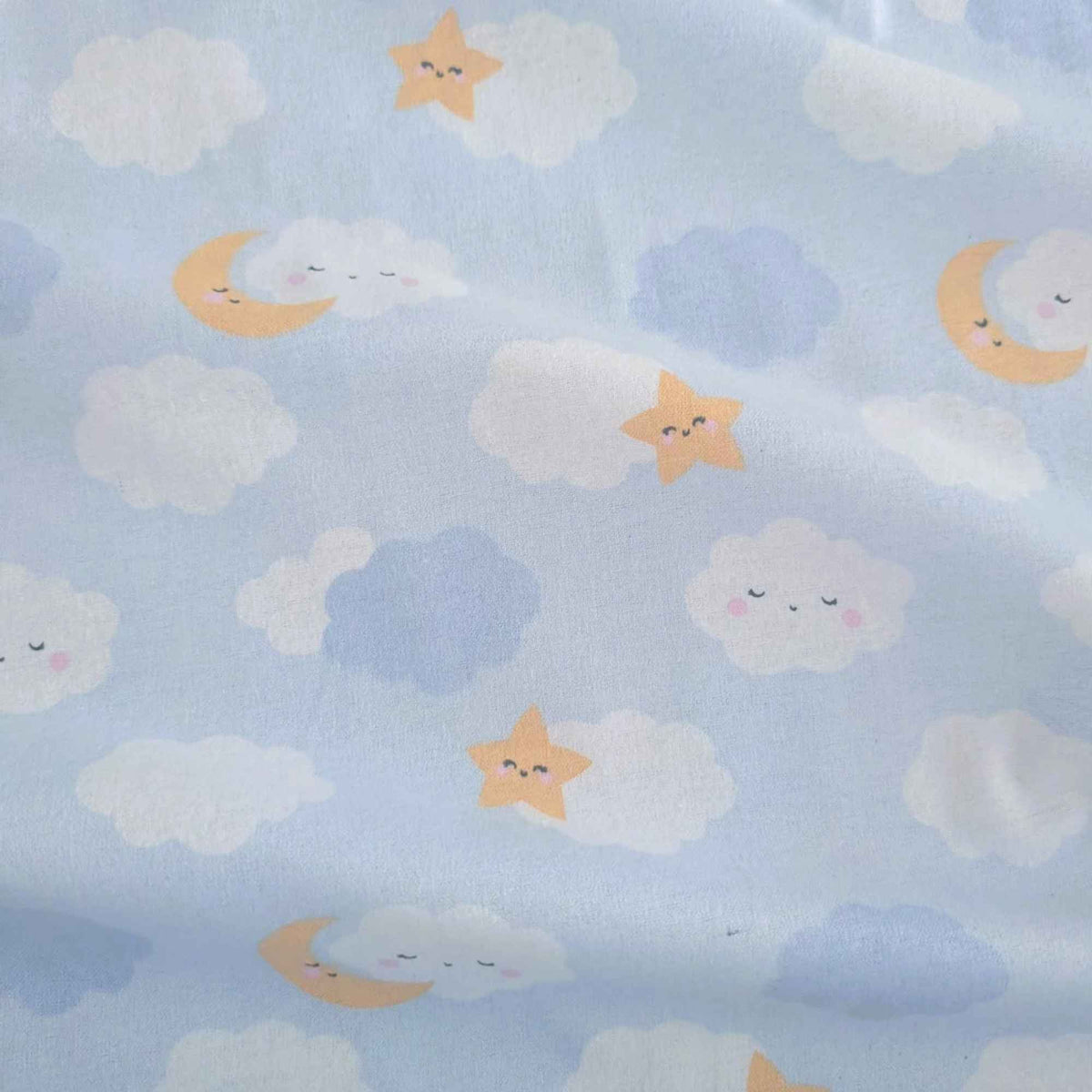 Light blue fabric with a cute cloud and moon pattern, featuring white fluffy clouds, soft blue clouds, and smiling yellow crescent moons and stars.