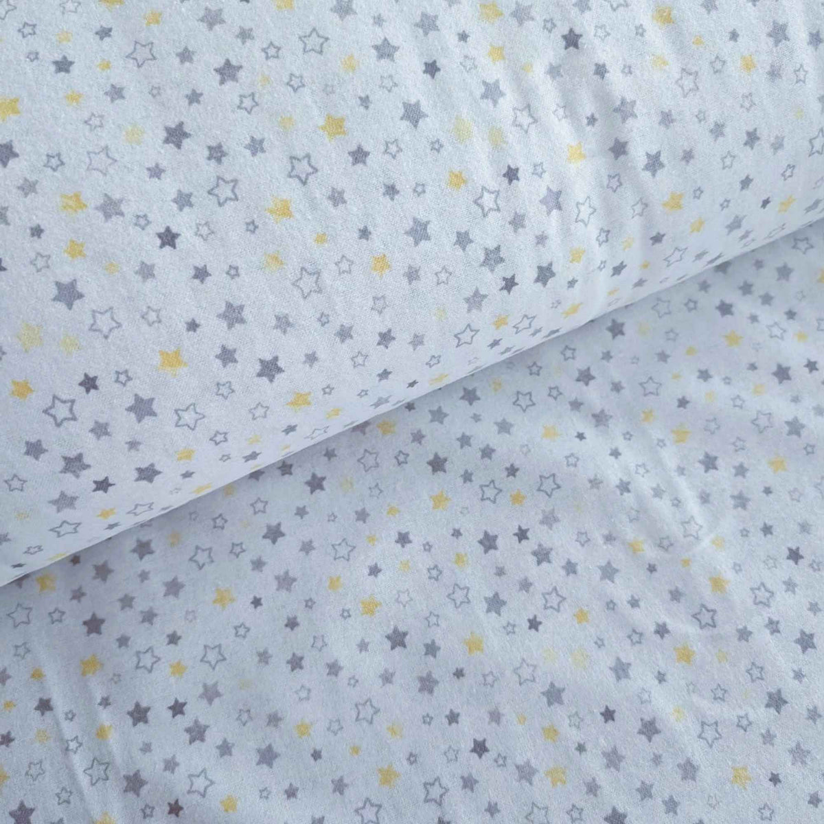 White fabric with a repeating pattern of small stars in gray and yellow, shown folded to display its texture and print.