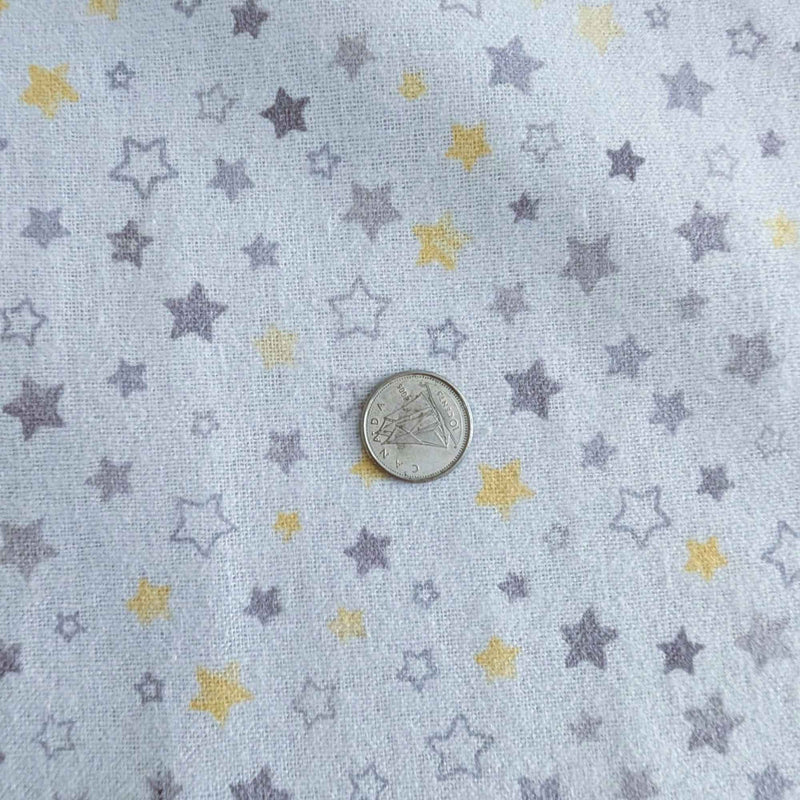 Light blue fabric with a pattern of small stars in lavender and yellow, shown with a silver coin for scale.