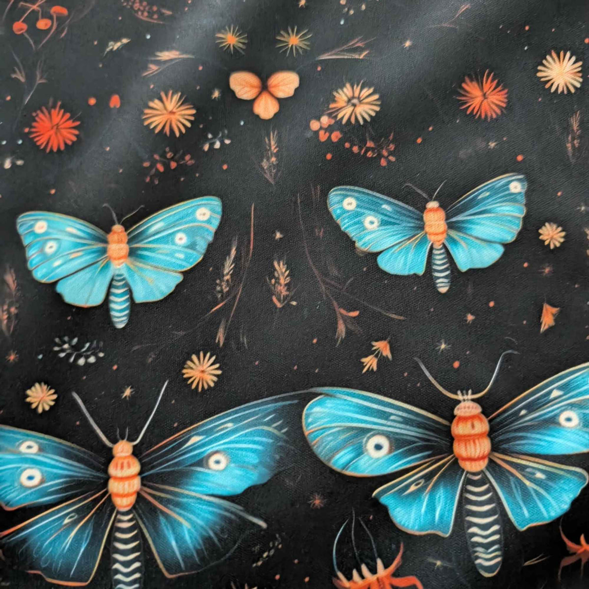 Midnight Blue Moths and Wildflowers exclusive waterproof PUL fabric with turquoise moths and orange flowers on a black background