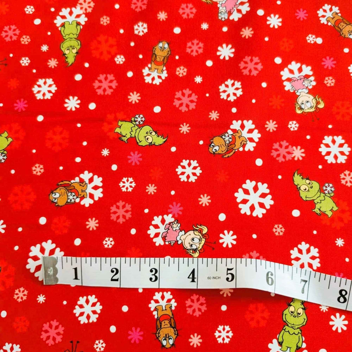 Little Grinch cotton fabric with Grinch characters and snowflakes on red