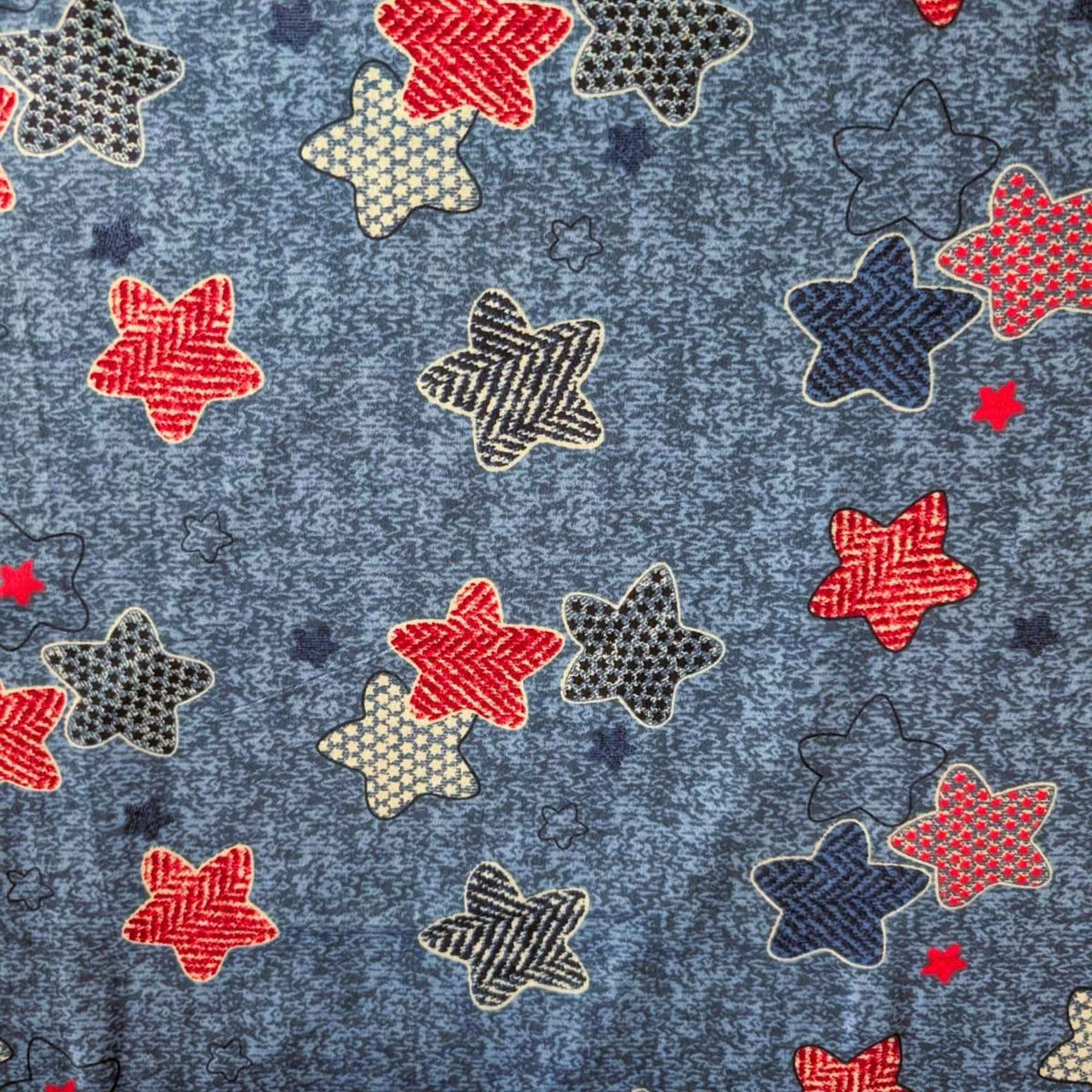 Star print cotton flannel with red, navy, black and cream patterned stars on a textured denim-look blue background.