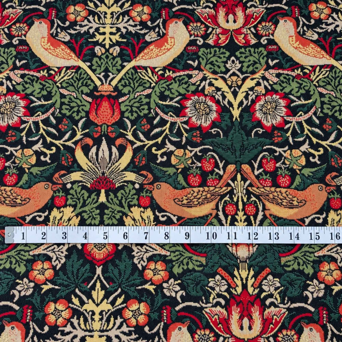 Black Gobelin tapestry fabric featuring golden birds, red strawberries, ornate flowers and scrolling green foliage.
