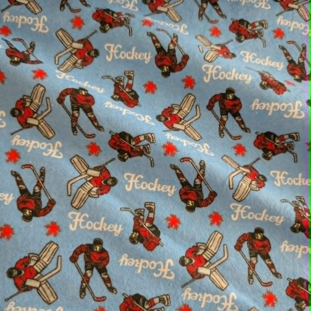 Blue hockey cotton flannel fabric featuring hockey players, goalies, hockey sticks, and hockey text on a soft brushed cotton background.