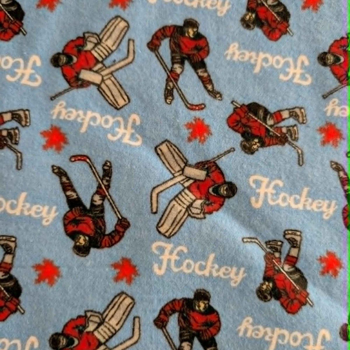 Blue hockey cotton flannel fabric featuring hockey players, goalies, hockey sticks, and hockey text on a soft brushed cotton background.