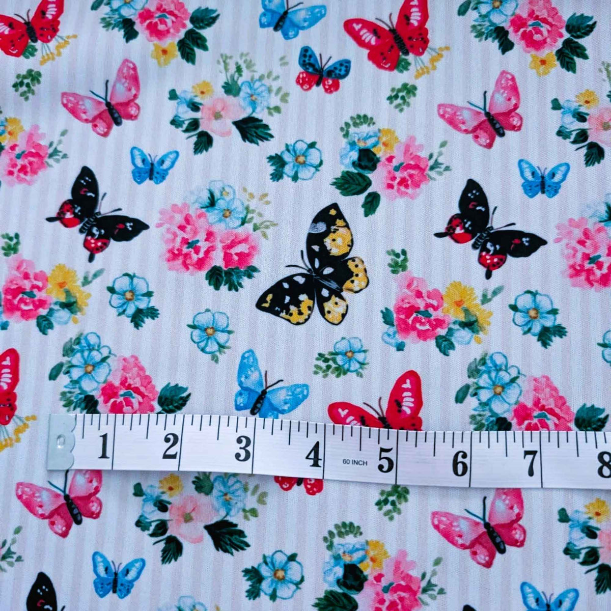 Colourful Butterfly Garden exclusive waterproof PUL fabric with blue, pink, red and yellow butterflies and flowers on yellow stripes