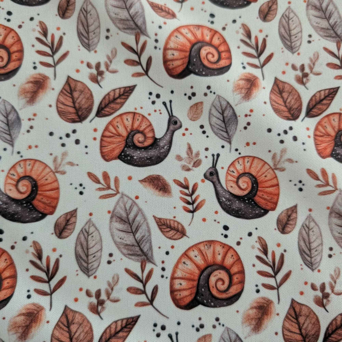 Woodland Snails and Autumn Leaves exclusive waterproof PUL fabric with orange-shelled snails and brown leaves on cream