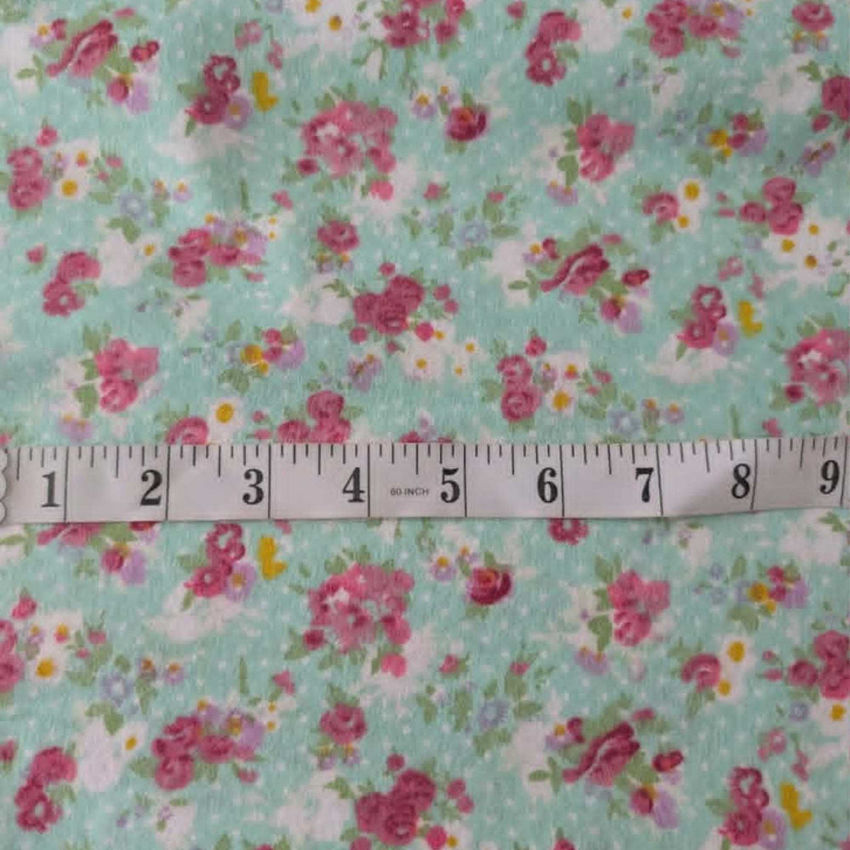 Double brushed flannel fabric featuring pink rose bouquets, delicate wildflowers, and floral sprigs on a soft mint green background.