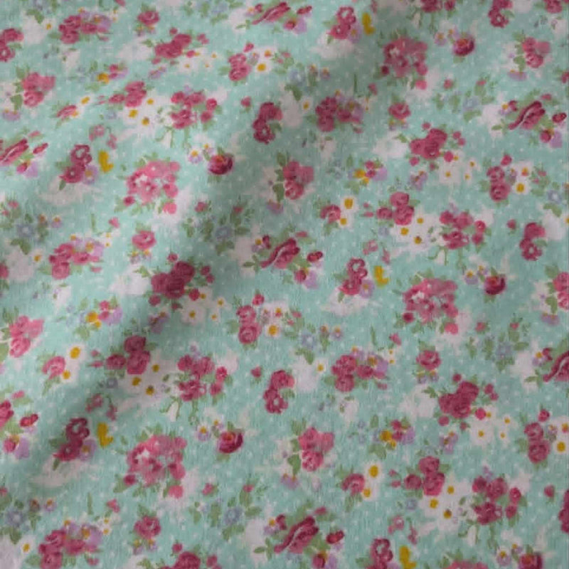 Double brushed flannel fabric featuring pink rose bouquets, delicate wildflowers, and floral sprigs on a soft mint green background.