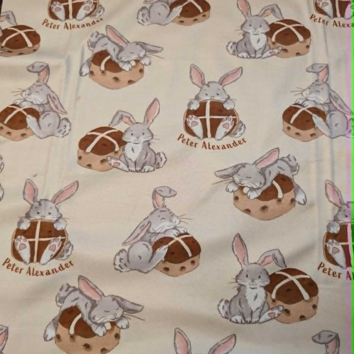 Double brushed flannel fabric featuring adorable bunny rabbits resting beside hot cross buns on a cream background.