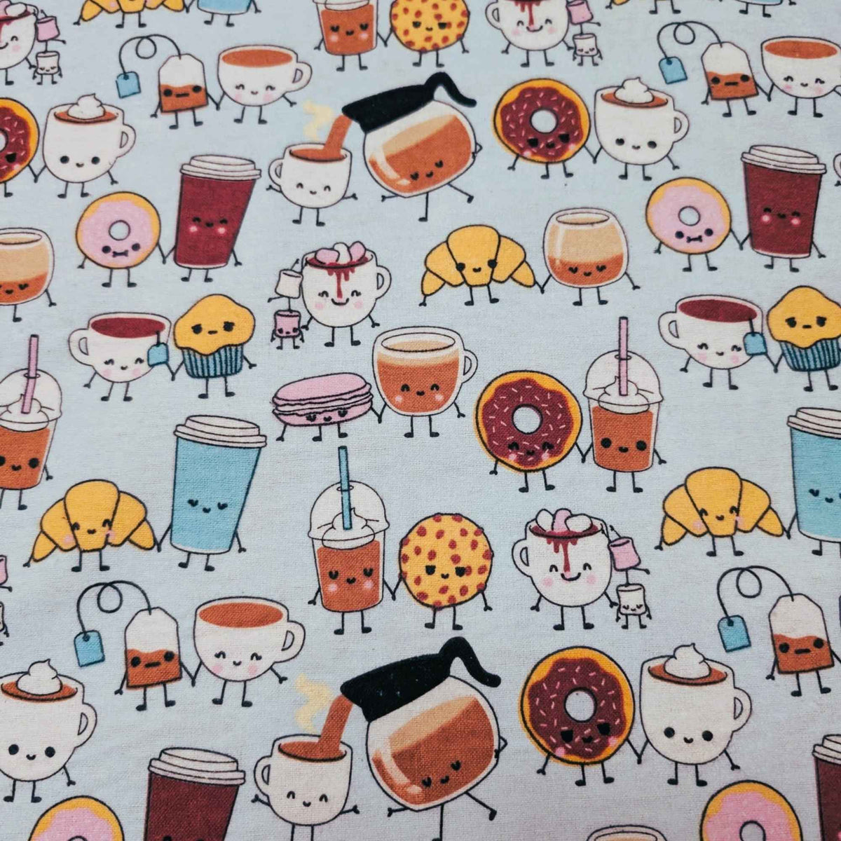 A close-up of a mint green fabric featuring a repeating cartoon pattern of various coffee-themed characters, including cappuccinos, lattes, iced drinks, croissants, muffins, macarons, and donuts, all with small faces and limbs.