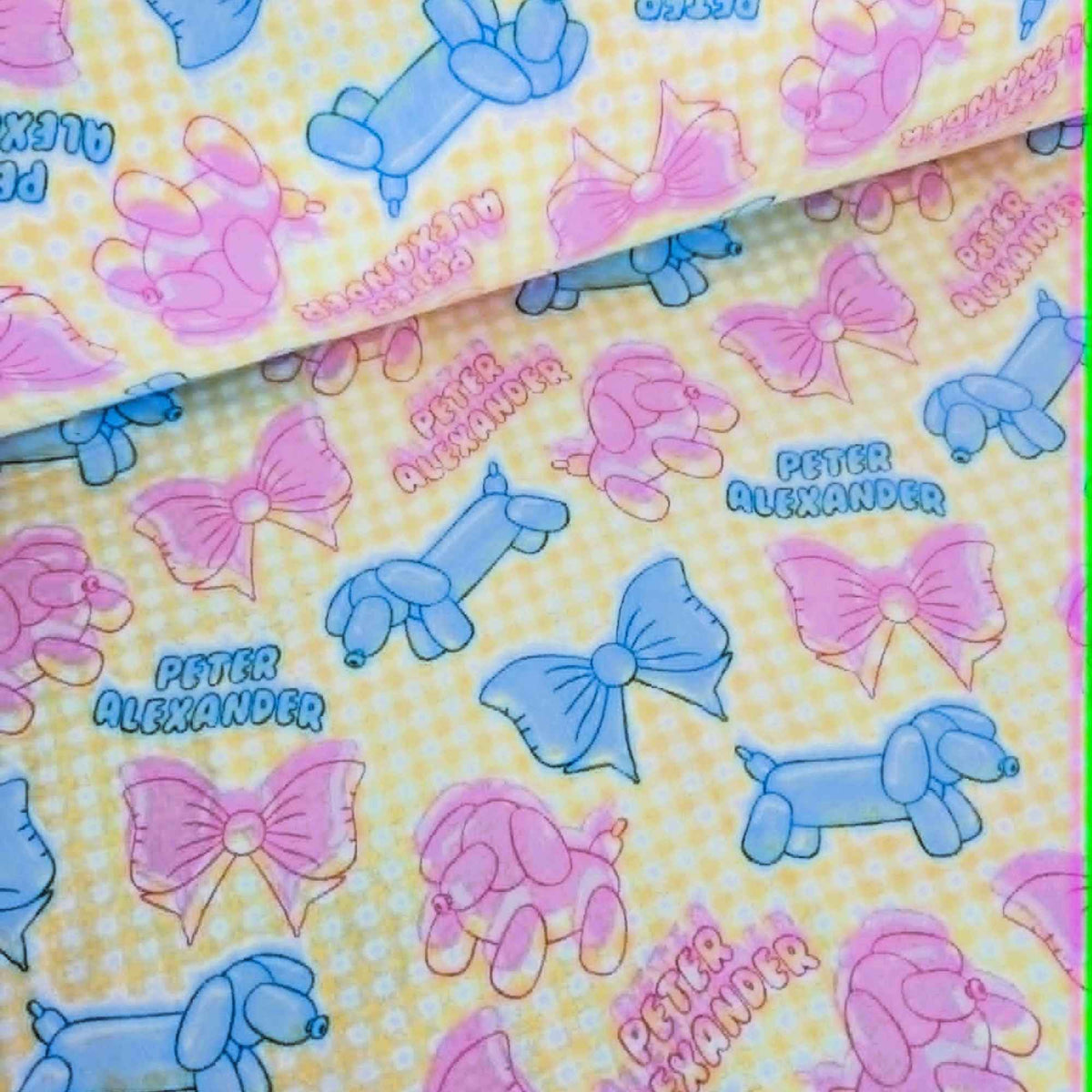 Double brushed flannel fabric featuring pastel balloon dogs, decorative bows, and a yellow gingham background in pink and blue tones.