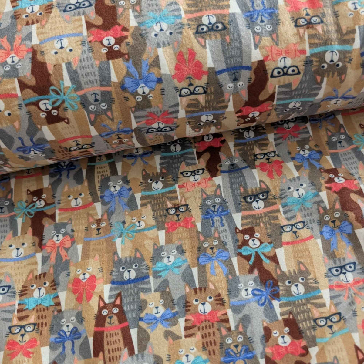 Double brushed flannel fabric featuring whimsical cats wearing colorful bows and collars on a light beige background.