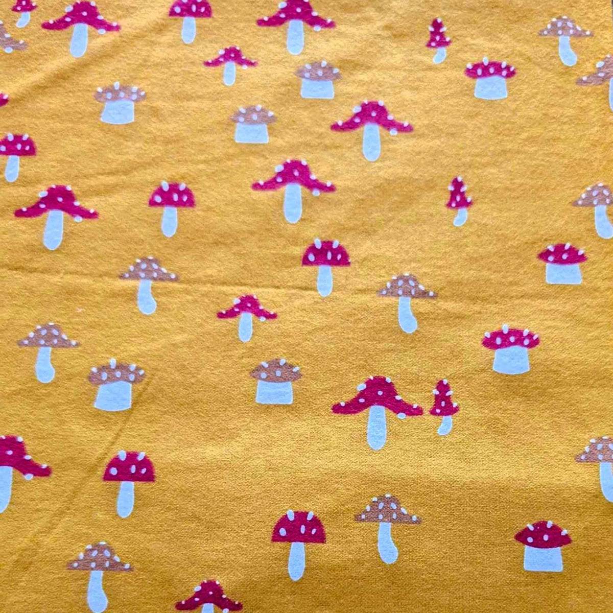 Golden yellow flannel fabric with whimsical red and tan mushroom print – 100% cotton, soft and cozy for quilting, pajamas, and crafts