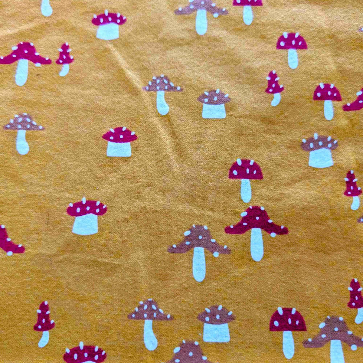 Golden yellow flannel fabric with whimsical red and tan mushroom print – 100% cotton, soft and cozy for quilting, pajamas, and crafts