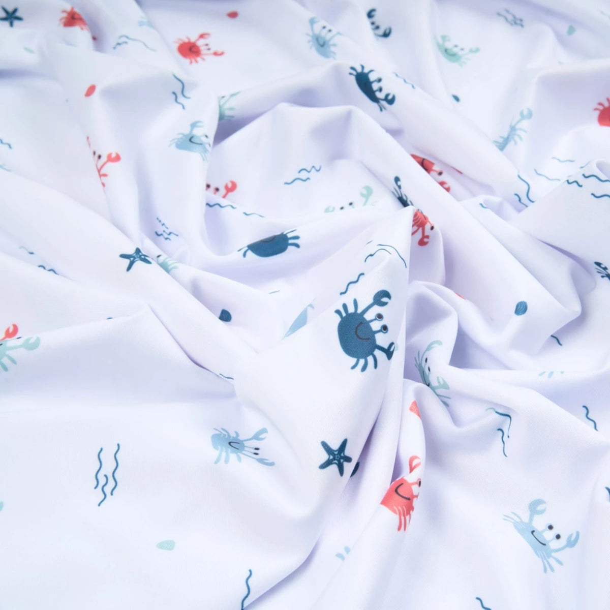 White swim fabric with playful red, blue, and mint crabs and beach motifs – Oeko-Tex certified stretch knit for kids' swimwear and ocean-themed projects