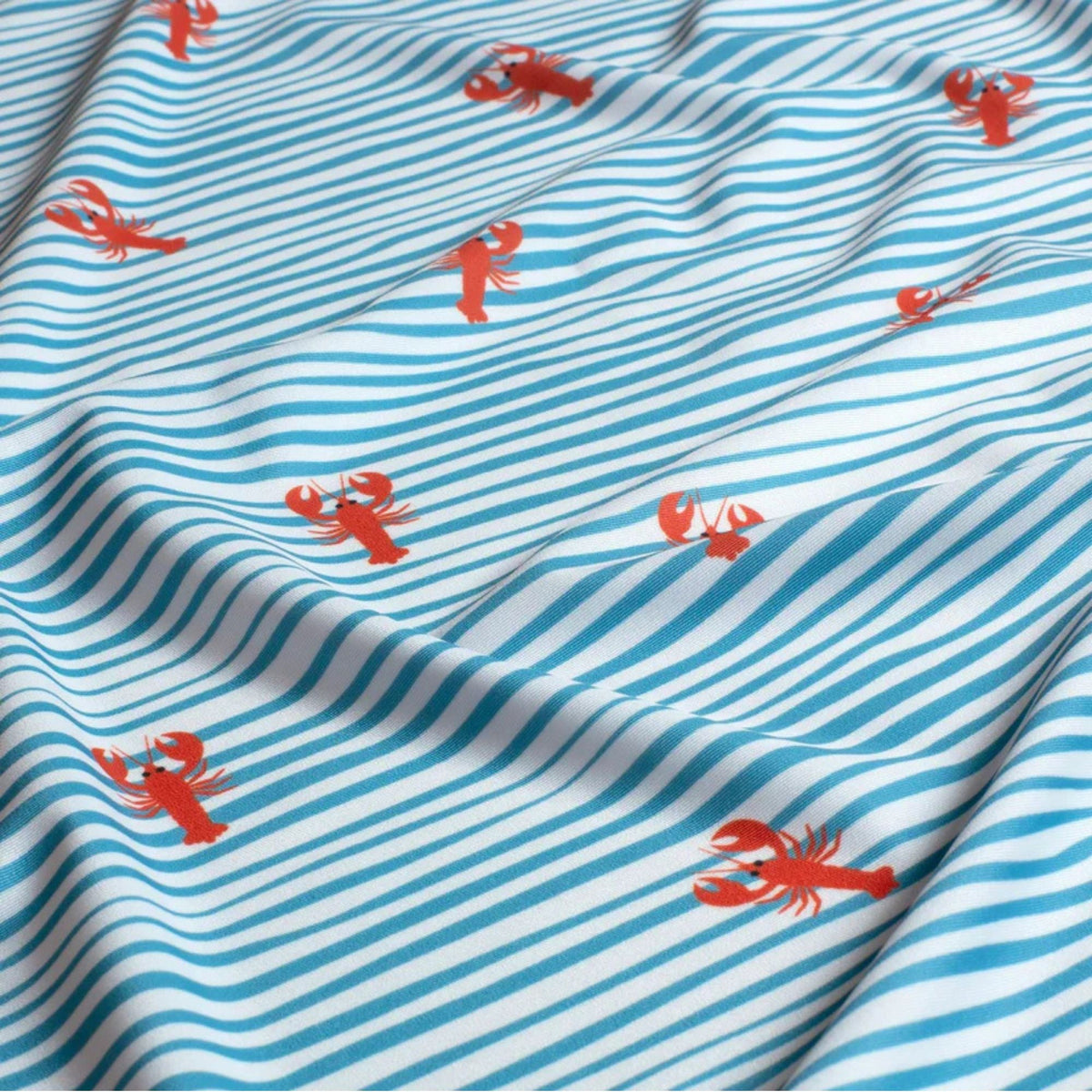 White swim fabric with playful red lobsters and blue wavy stripes – Oeko-Tex certified stretch knit for swimwear, kids’ beachwear, and nautical-themed projects


