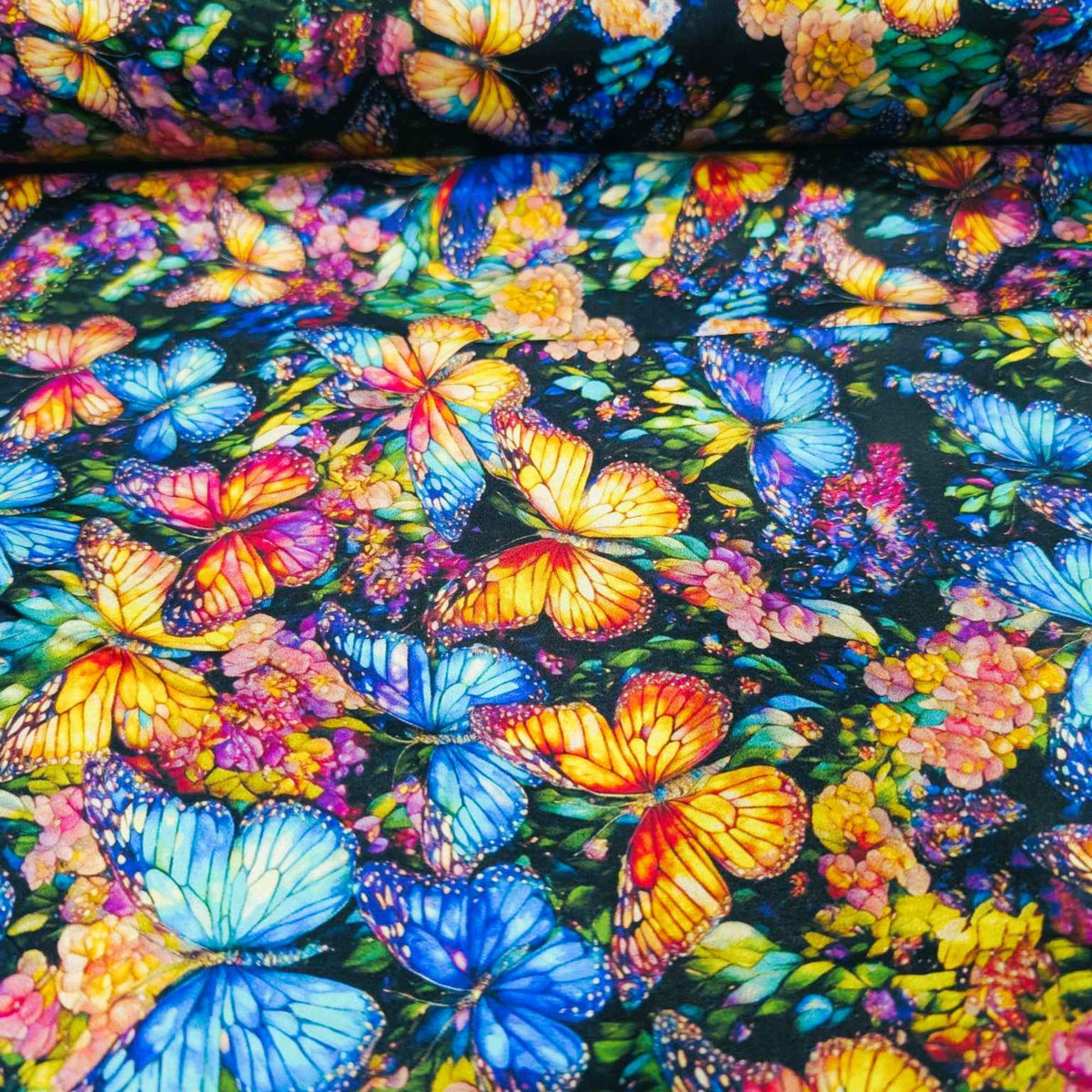 Stained glass butterfly fabric with vibrant blue, orange, and multicolored butterflies on a floral background – Gigi in the Garden 60-inch wide cotton backing